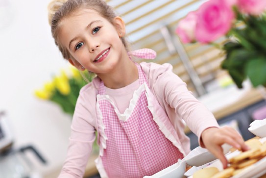 Little girl with cookies in a pink apron
