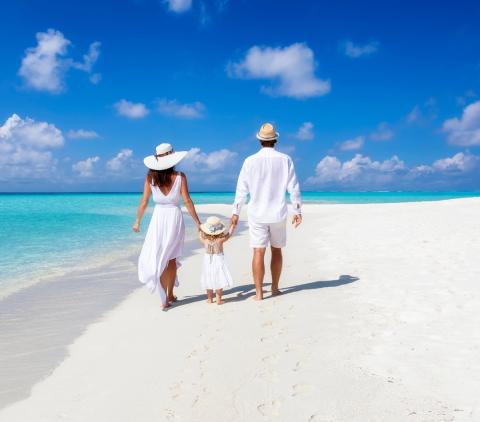 mum and dad with a little girl walking on the beach