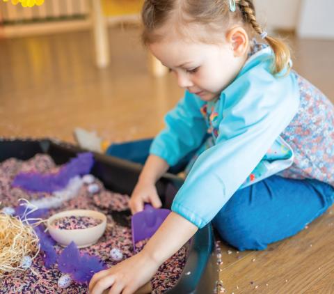 Girl playing in a sensory play tray.