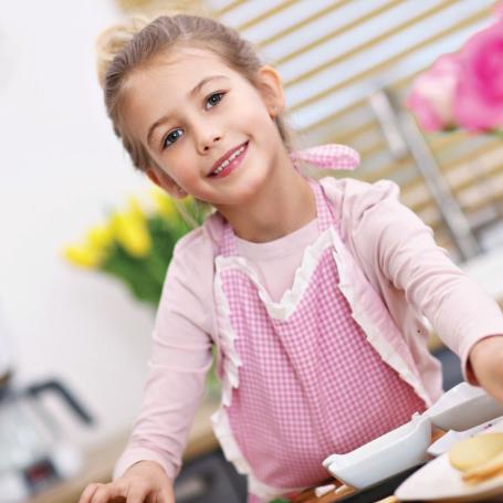 little girl with cookies in a pink apron