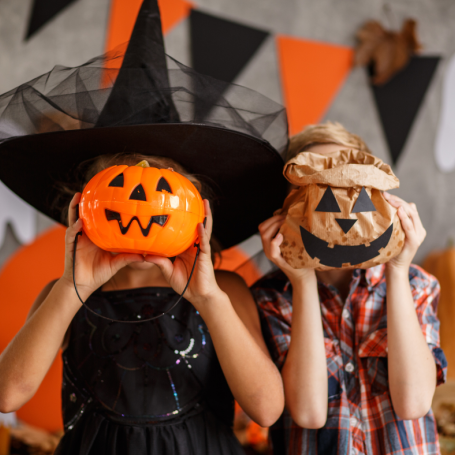 Two children holding up halloween bowls