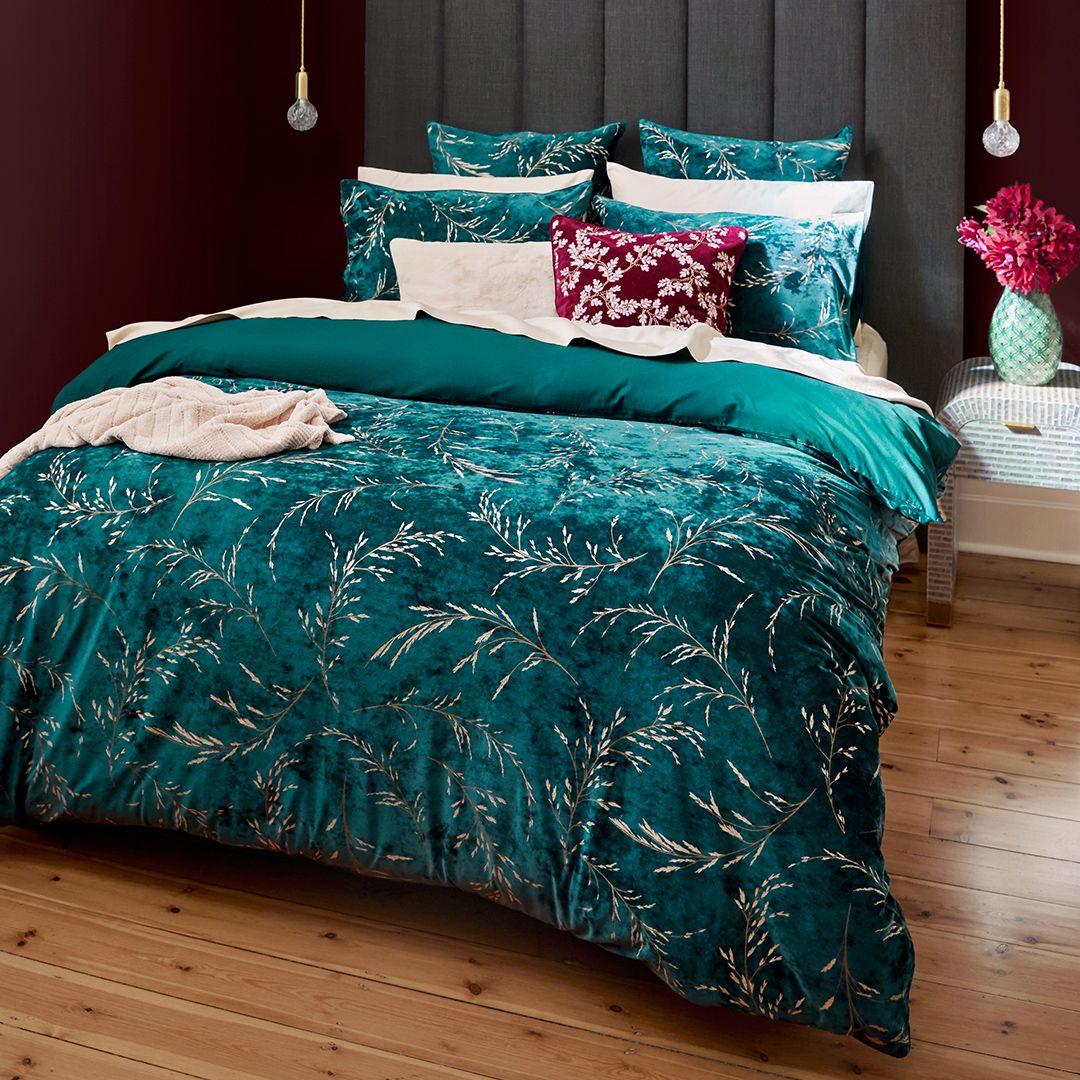 Bedroom with a blue floral quilt, matching pillows, and a bedside table with a floral arrangement.