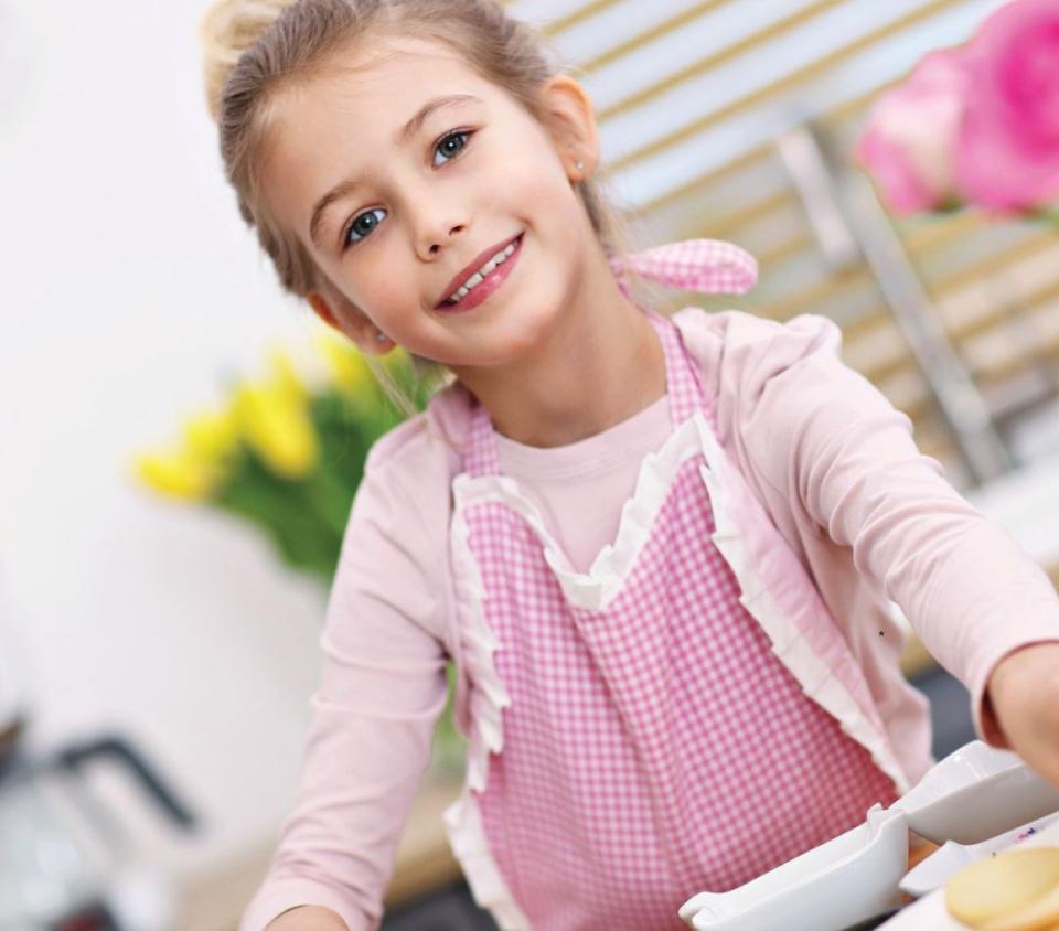 little girl with cookies in a pink apron