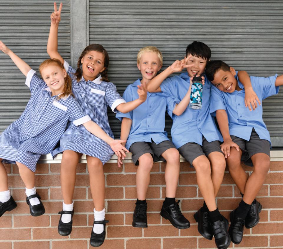 School kids sitting on a brick wall