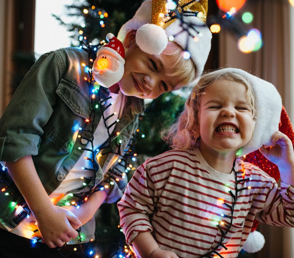 Kids smiling in front of a Christmas tree